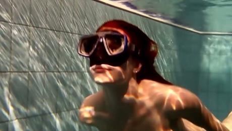 Hot redhead babe in the diver mask swimming under water